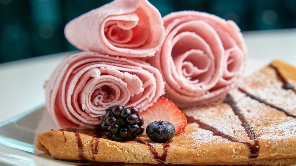 Rolled strawberry ice cream with fresh berries on a crepe. Perfect for dessert lovers.